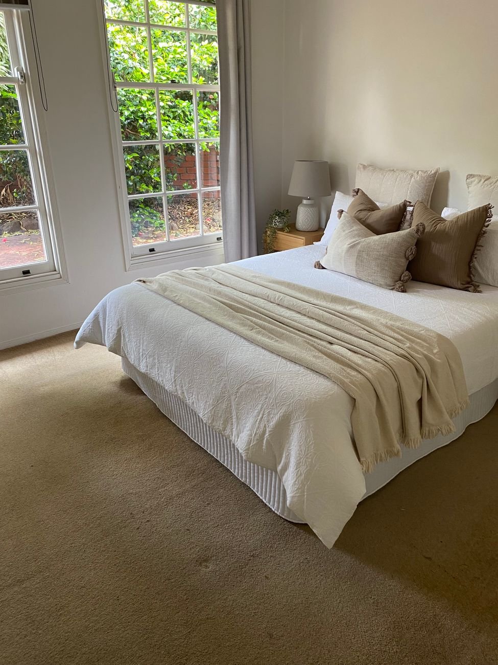 Bright bedroom featuring a neatly made bed with warm tones and soft decor.