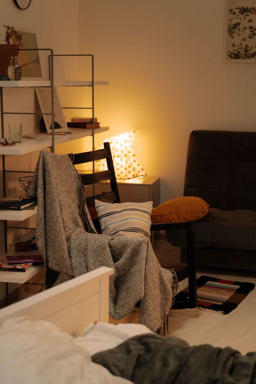 A cozy reading nook with cushions, blanket, and warm lighting for relaxation.